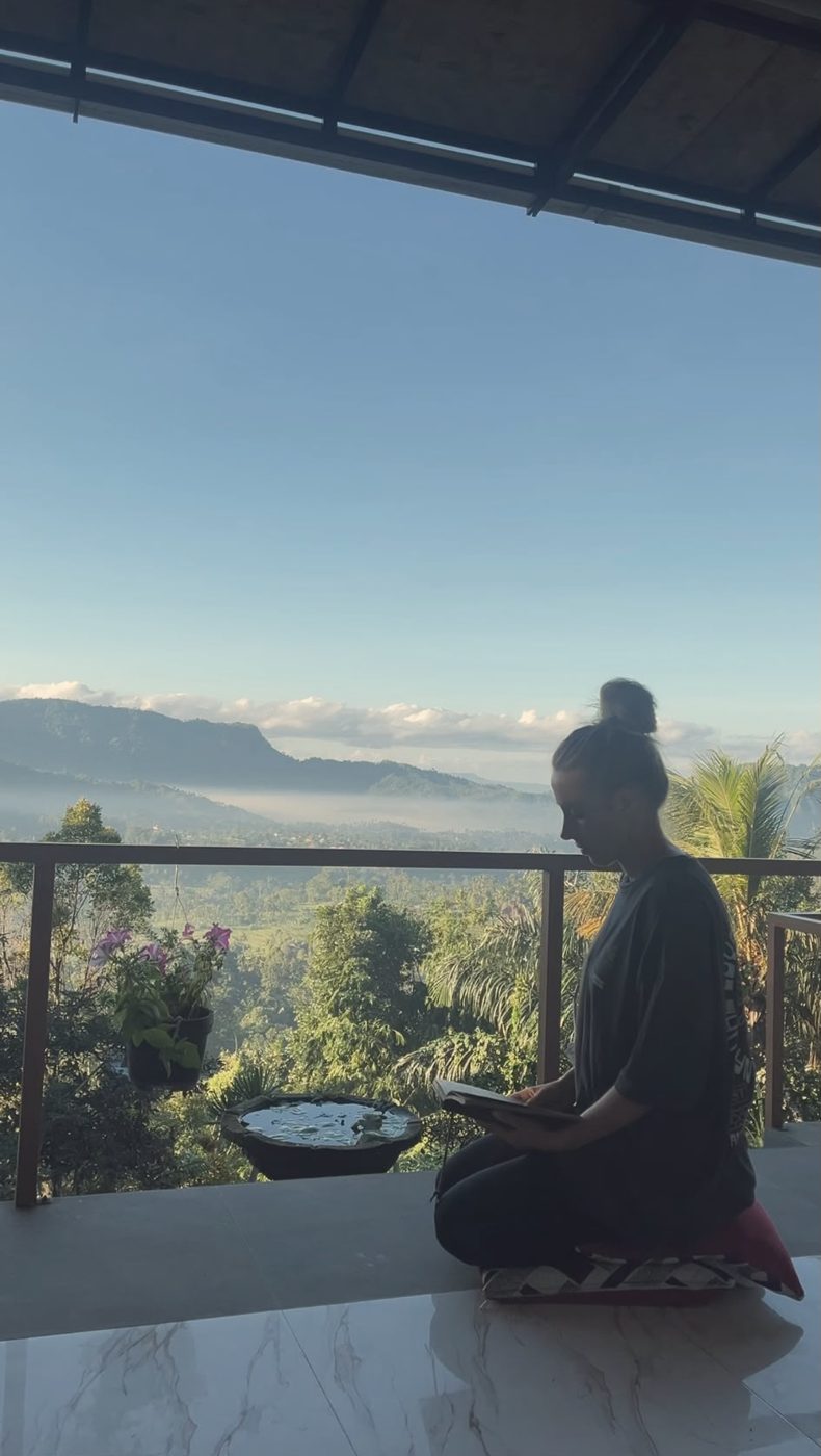 Kélya en train de lire sur un balcon face aux montagnes